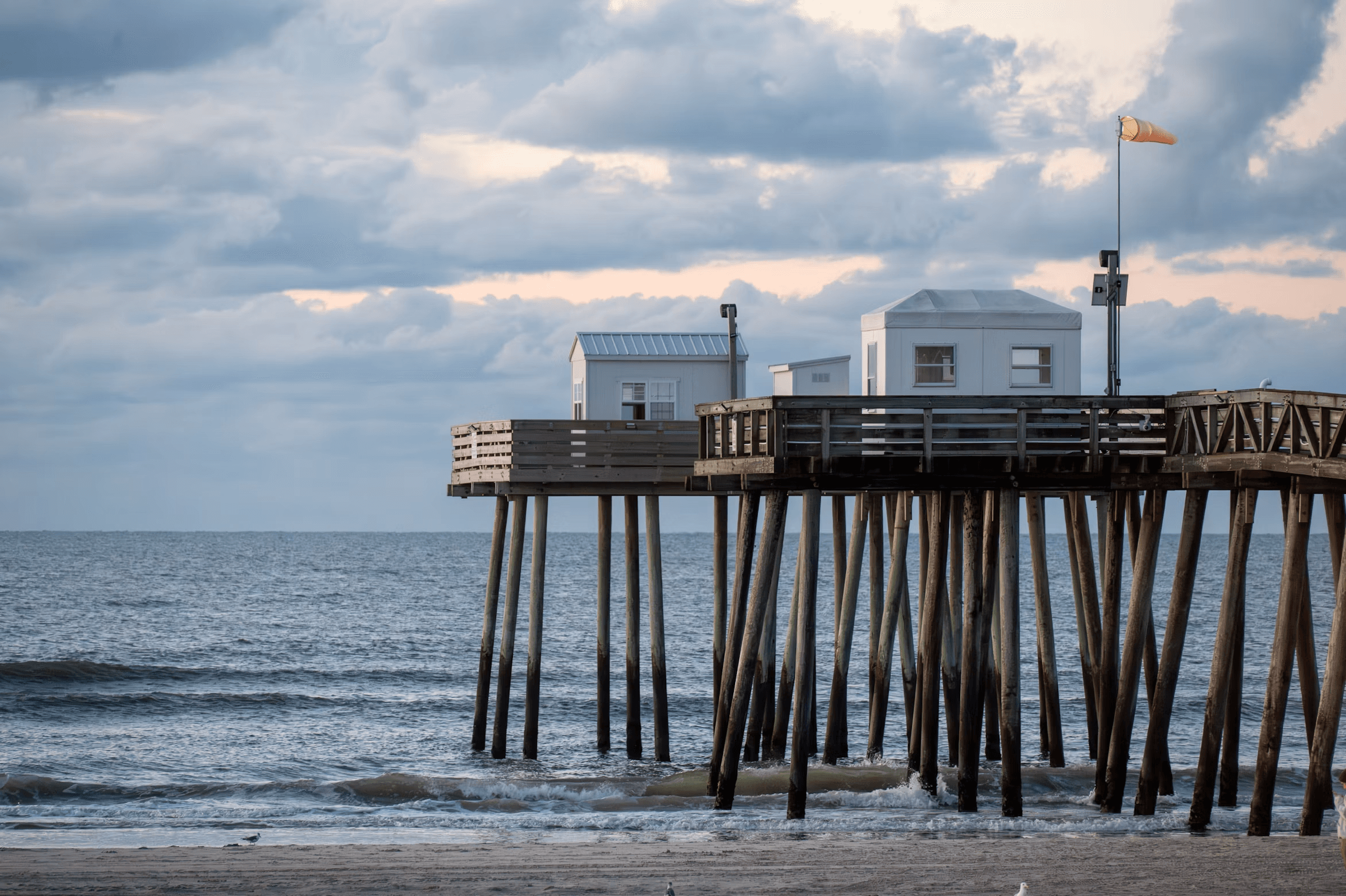 The Ocean City pier and fishing club buildings above the Atlantic under coastal clouds.